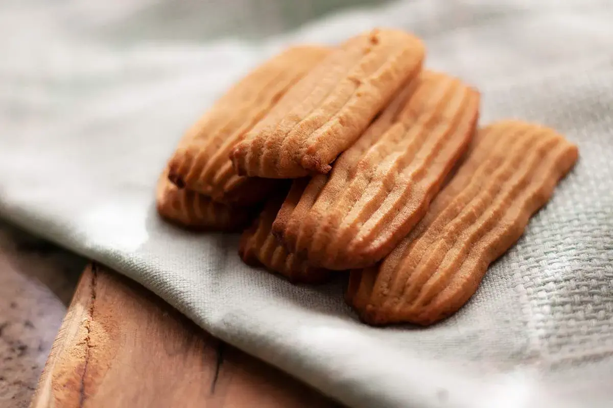Galletas de mantequilla receta: deliciosas galletas doradas con surcos, apiladas sobre una tela clara.