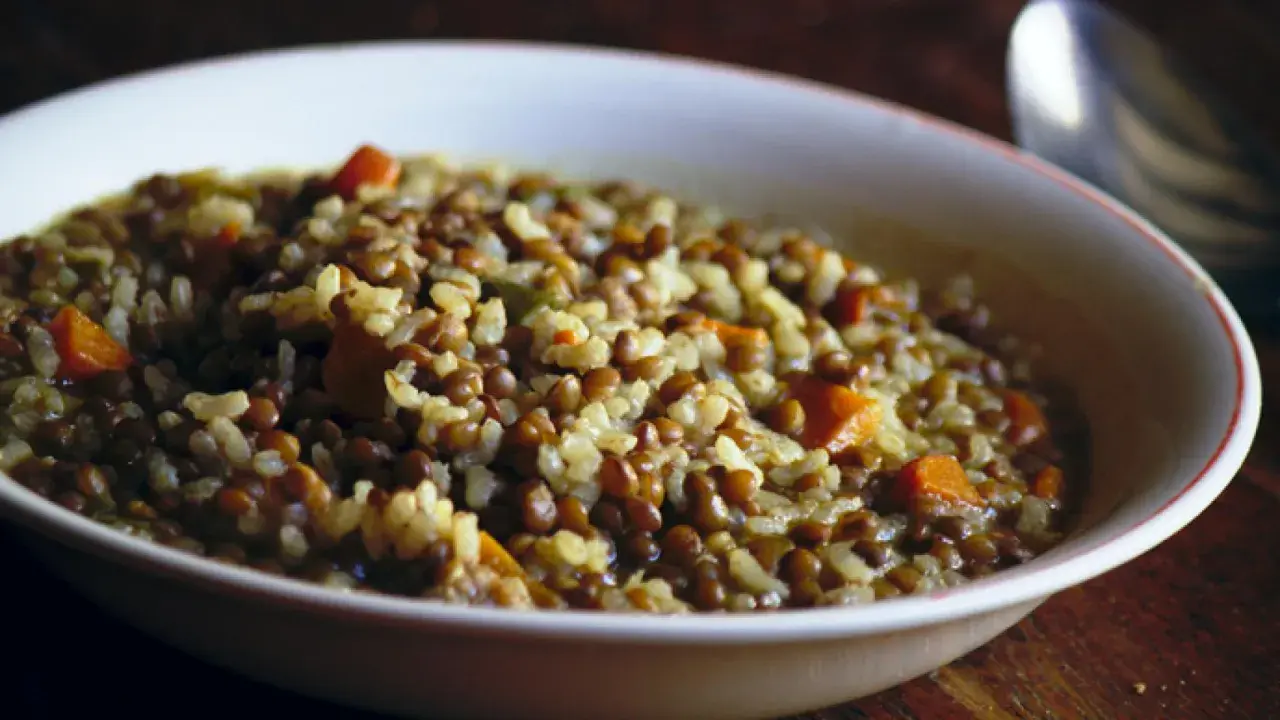 Un plato humeante de lentejas con arroz y trozos de zanahoria, listo para ser disfrutado.