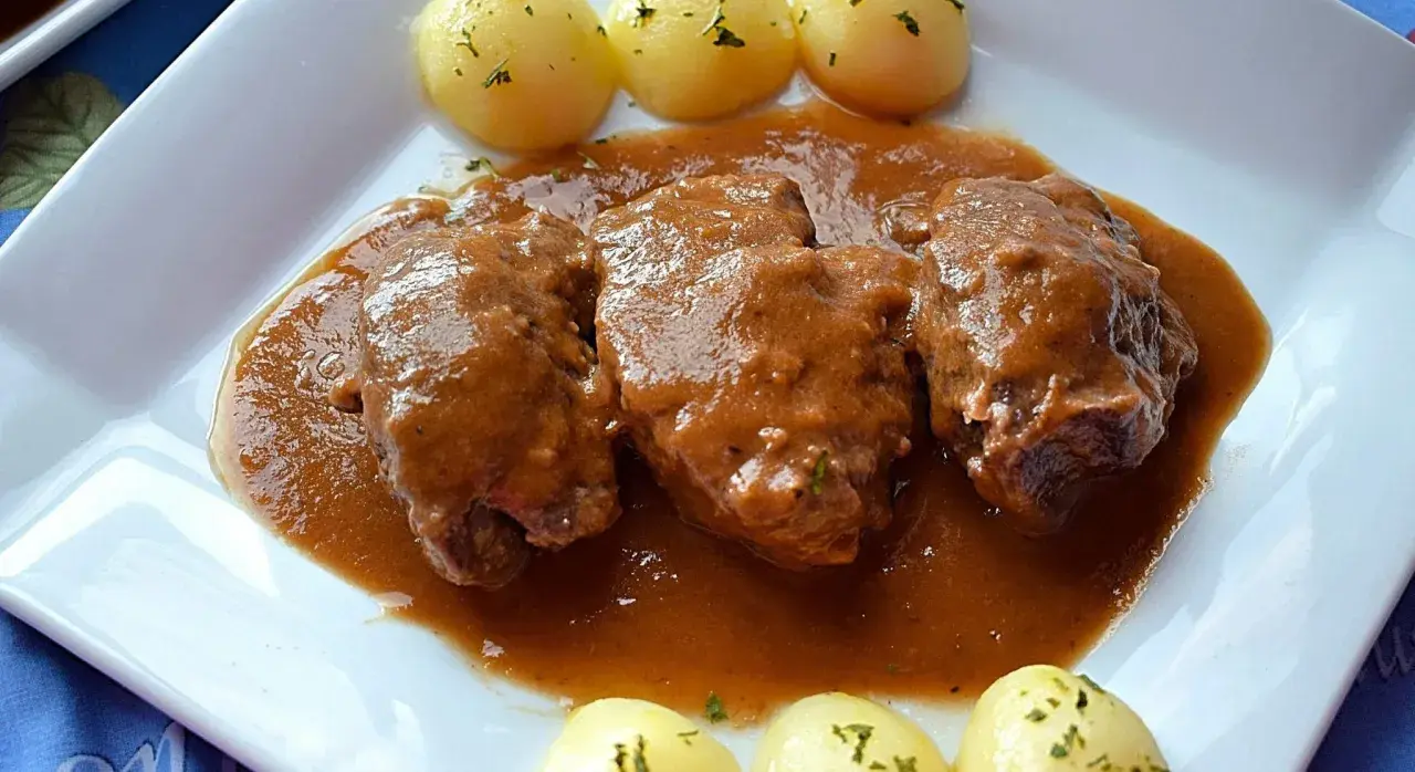 Carrilleras de ternera estofadas en salsa, acompañadas de patatas cocidas y espolvoreadas con perejil. Un plato casero que invita a disfrutar.
