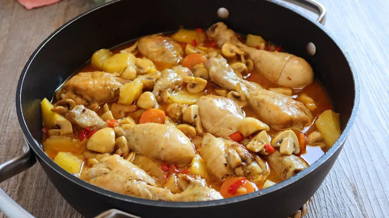 Estofado de pollo casero con patatas, champiñones y zanahorias en una sartén. Un plato reconfortante y delicioso.