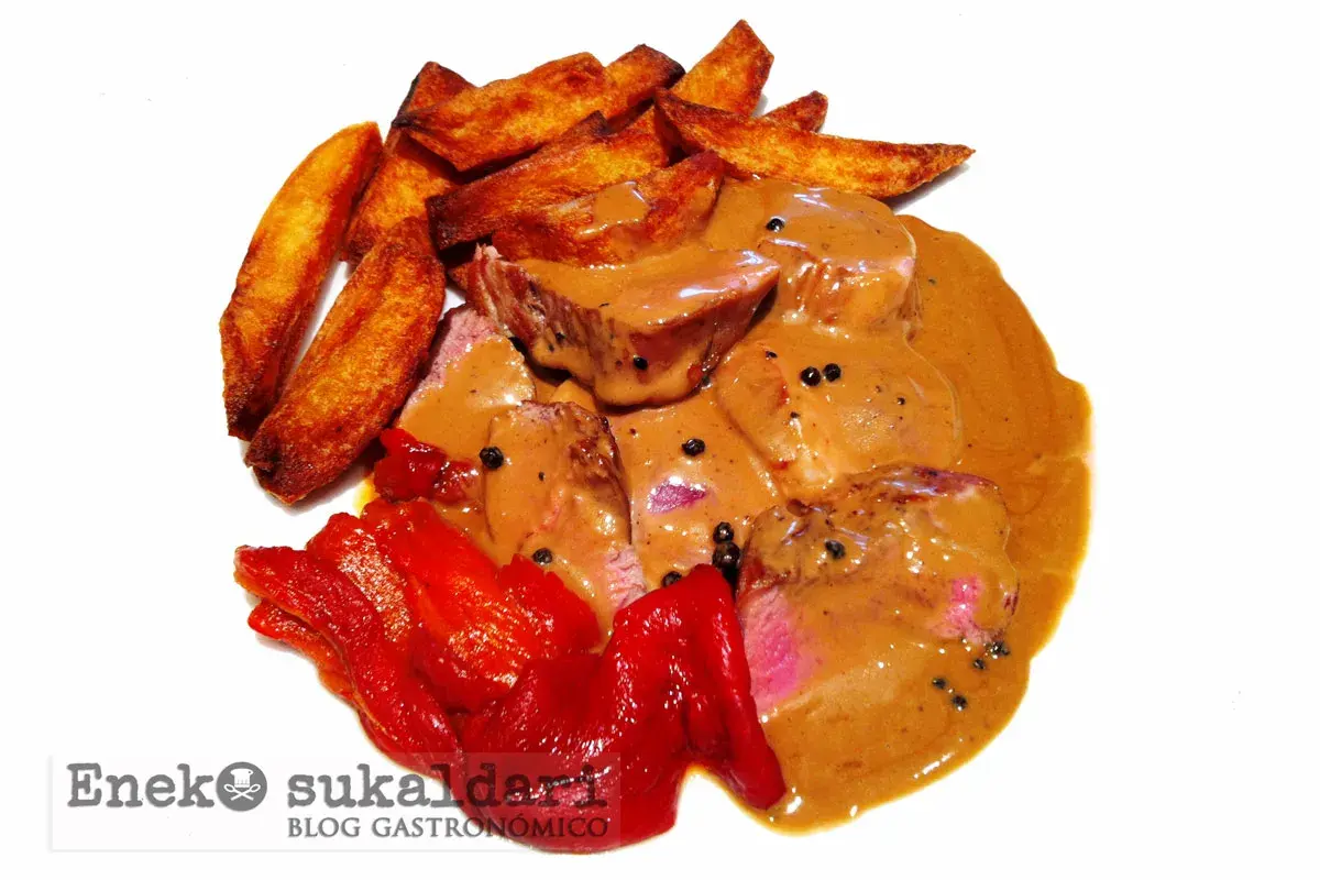 Delicioso solomillo a la pimienta bañado en salsa cremosa, acompañado de patatas rústicas y pimientos rojos asados.