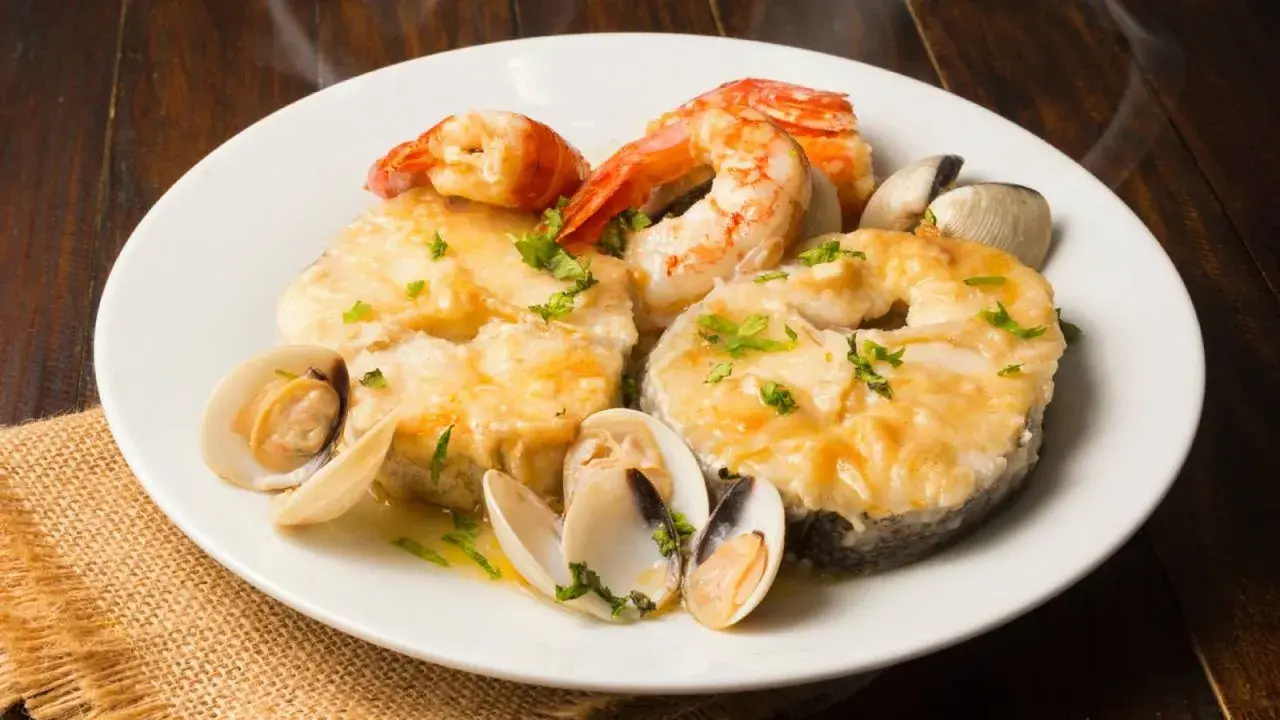 Merluza a la marinera con almejas y gambas, un plato delicioso y aromático, listo para disfrutar.