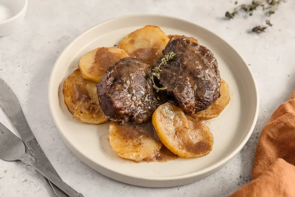 Deliciosas galtas al horno, tiernas y jugosas, servidas sobre rodajas de patata doradas y bañadas en su propia salsa.