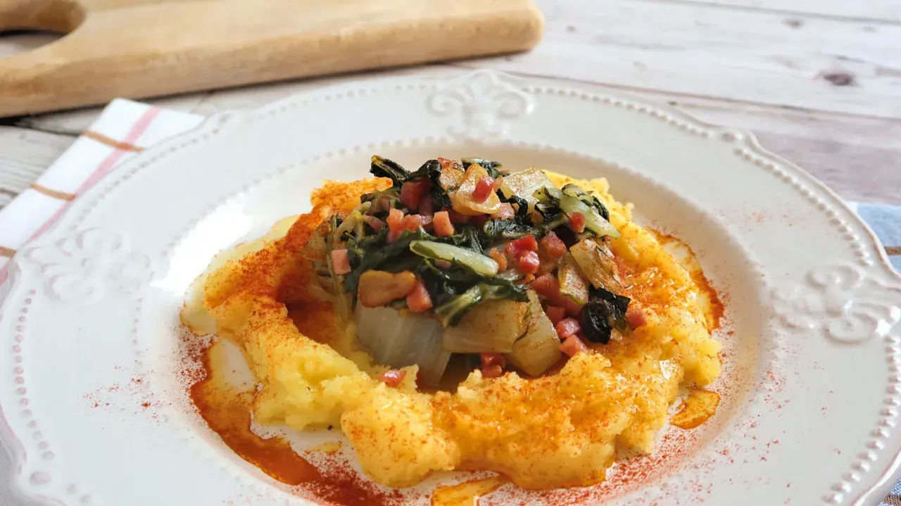 Puré de patatas cremoso con un sofrito de acelgas y trocitos de jamón, espolvoreado con pimentón. Un plato reconfortante de acelgas con patatas.