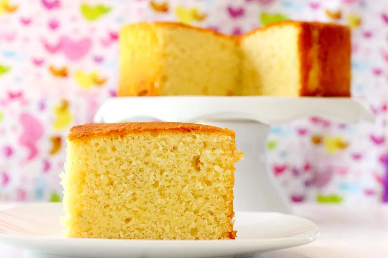 Un trozo de bizcocho de yogur, la receta de la abuela, esponjoso y dorado, sobre un plato blanco.