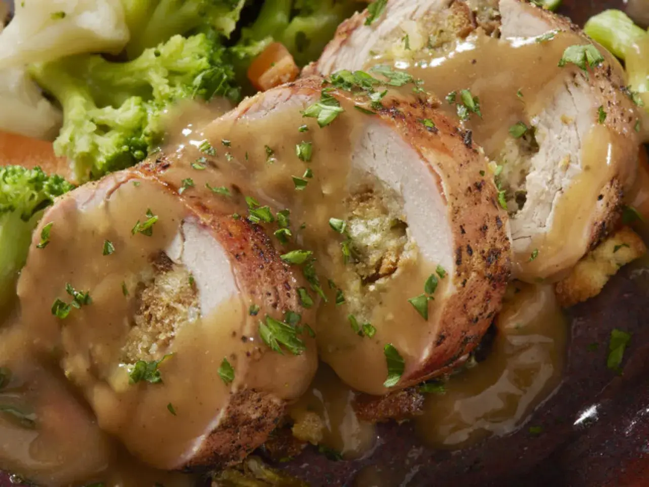 Jugoso solomillo de pollo relleno, bañado en salsa y acompañado de brócoli y zanahoria.