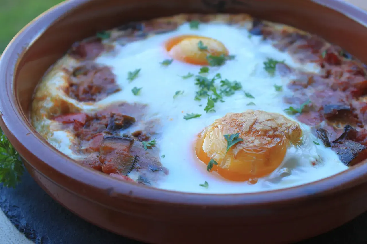 Un plato de samfaina con huevos escalfados, decorado con perejil fresco. ¡Una delicia para probar esta samfaina recepta!