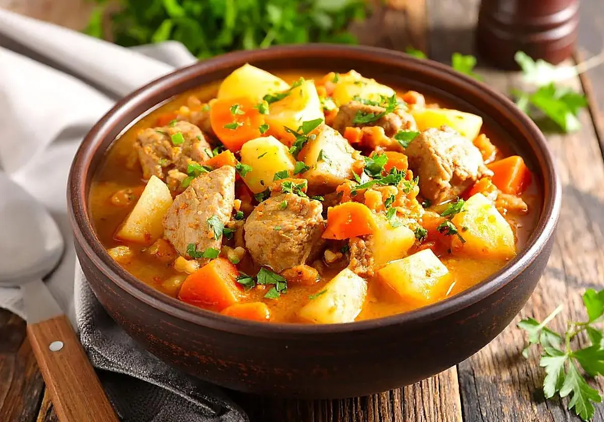 Un reconfortante tazón de patatas guisadas con trozos de carne tierna, zanahorias y perejil fresco.