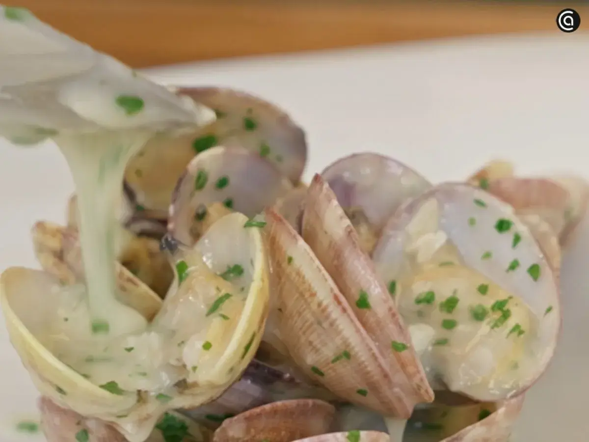 Almejas en salsa verde, con una cremosa salsa blanca y perejil picado, listas para ser servidas.