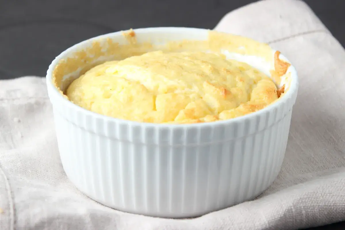 Un esponjoso soufflé de patatas recién horneado en un ramekin blanco, listo para ser disfrutado.