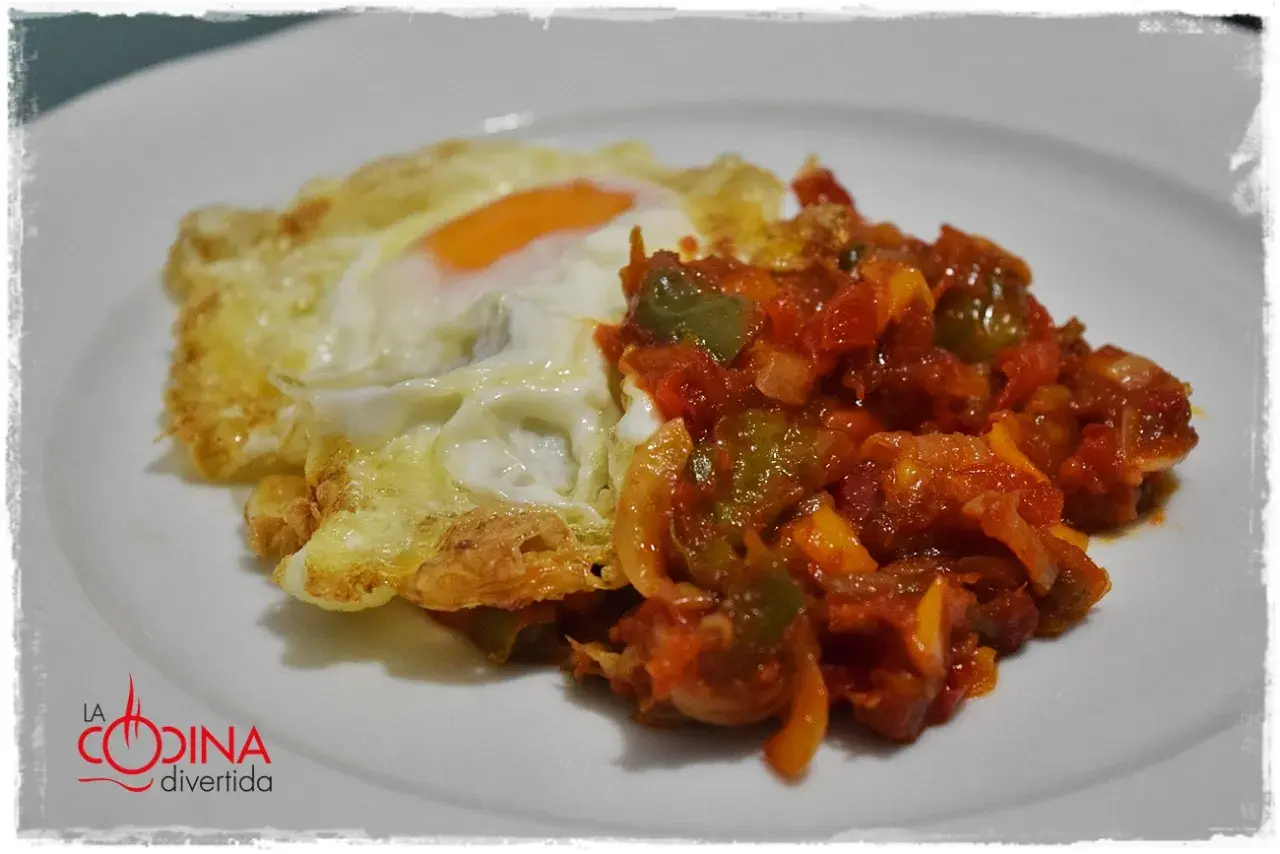 Huevo frito con un sofrito de pimientos y tomate. Un plato sencillo y delicioso, perfecto para cualquier momento del día.
