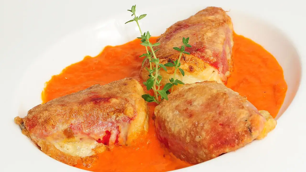 Pimientos del piquillo rellenos de bacalao, rebozados y servidos en una cremosa salsa de pimientos. Decorados con tomillo fresco.