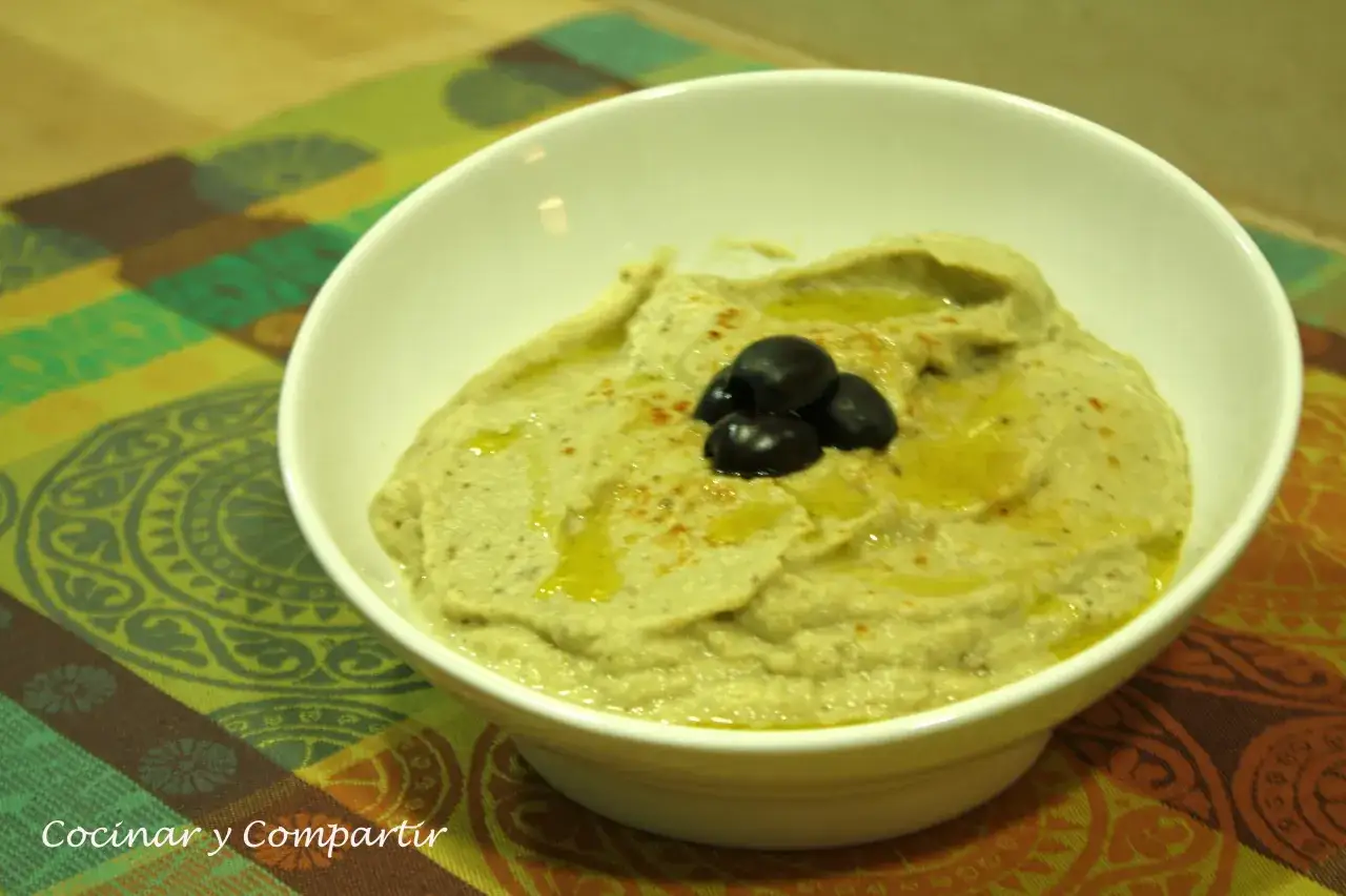 Un cremoso puré de berenjena con aceite de oliva y aceitunas negras, listo para disfrutar.