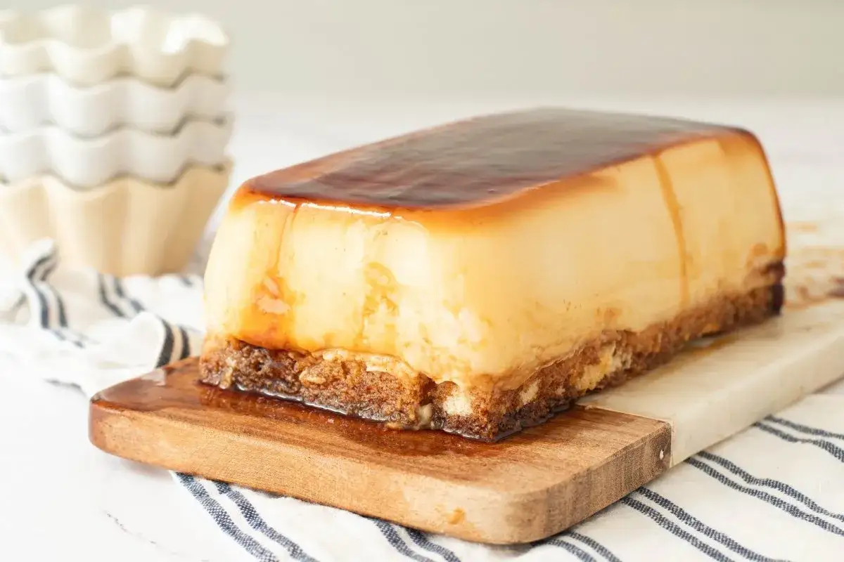 Tarta de cuajada dorada y brillante, con base crujiente, servida en tabla de madera.