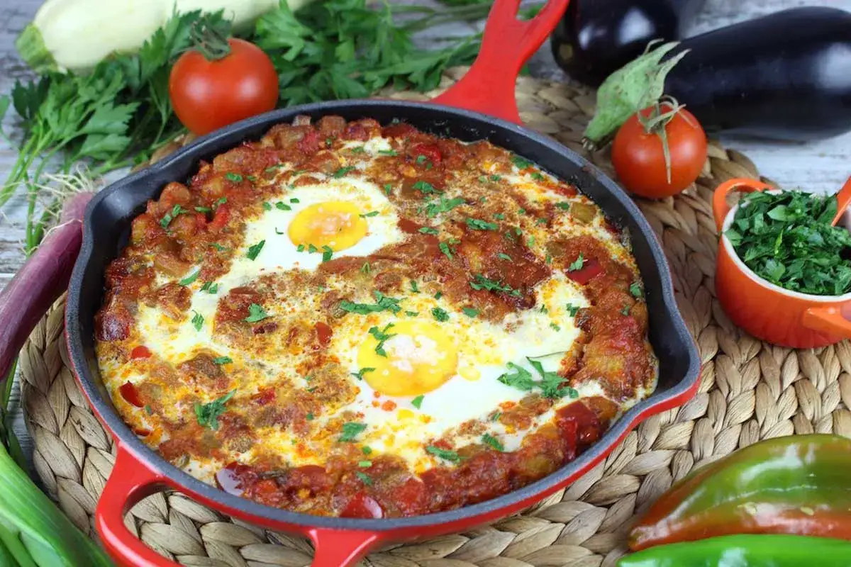 Sabrosa cazuela de verduras a la plancha con huevos escalfados, adornada con perejil fresco.