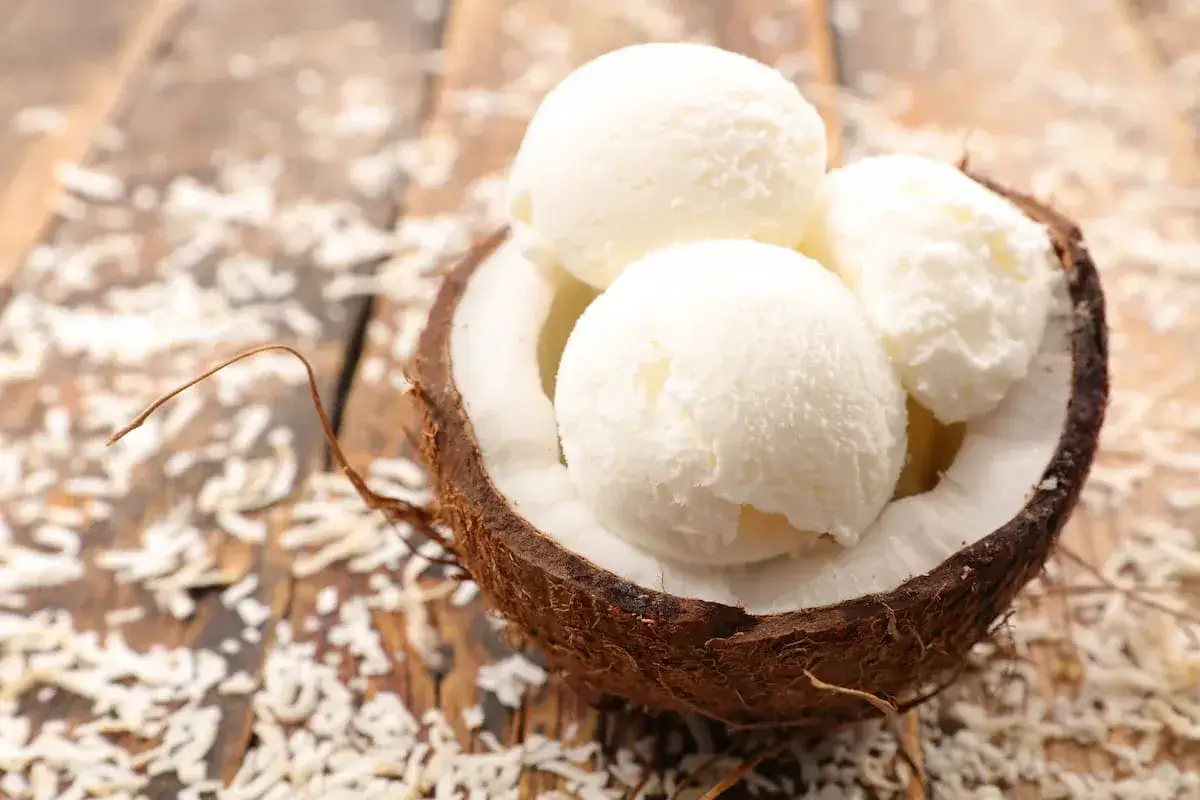 Tres bolas de helado de coco servidas en una c&aacute;scara de coco. Una delicia refrescante para aprender como hacer helado casero.