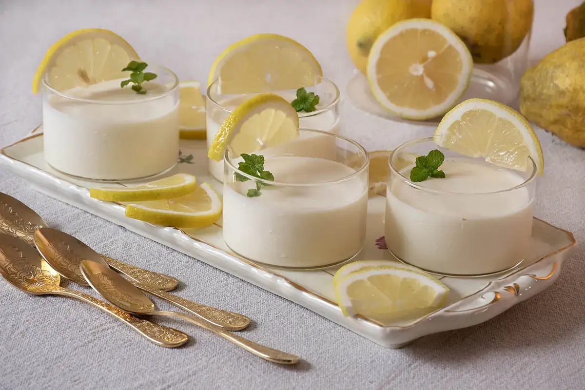 Deliciosa crema de limón servida en vasos con rodajas de limón y hojas de menta.