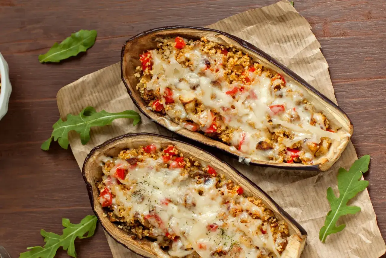 Dos mitades de berenjenas rellenas con cusc&uacute;s, pimientos y queso derretido, cocinadas en airfryer.