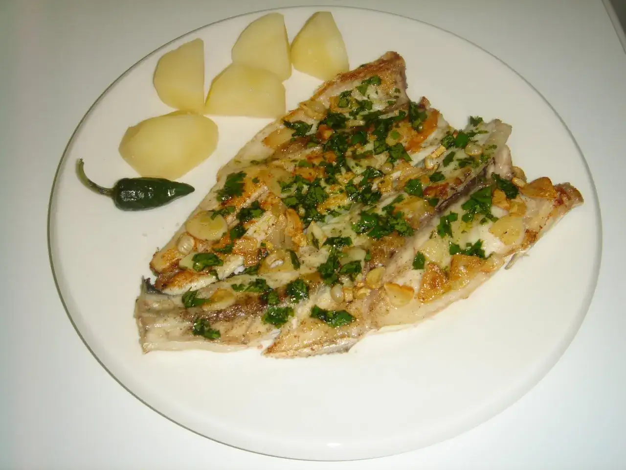 Lubina a la espalda con patatas y pimiento verde. Un plato delicioso y saludable.