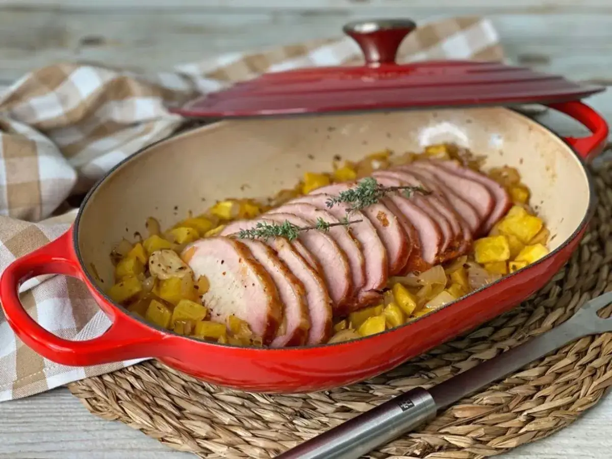 Lomo adobado jugoso y tierno, servido sobre patatas y cebolla en una cazuela roja. ¡Un plato casero delicioso!