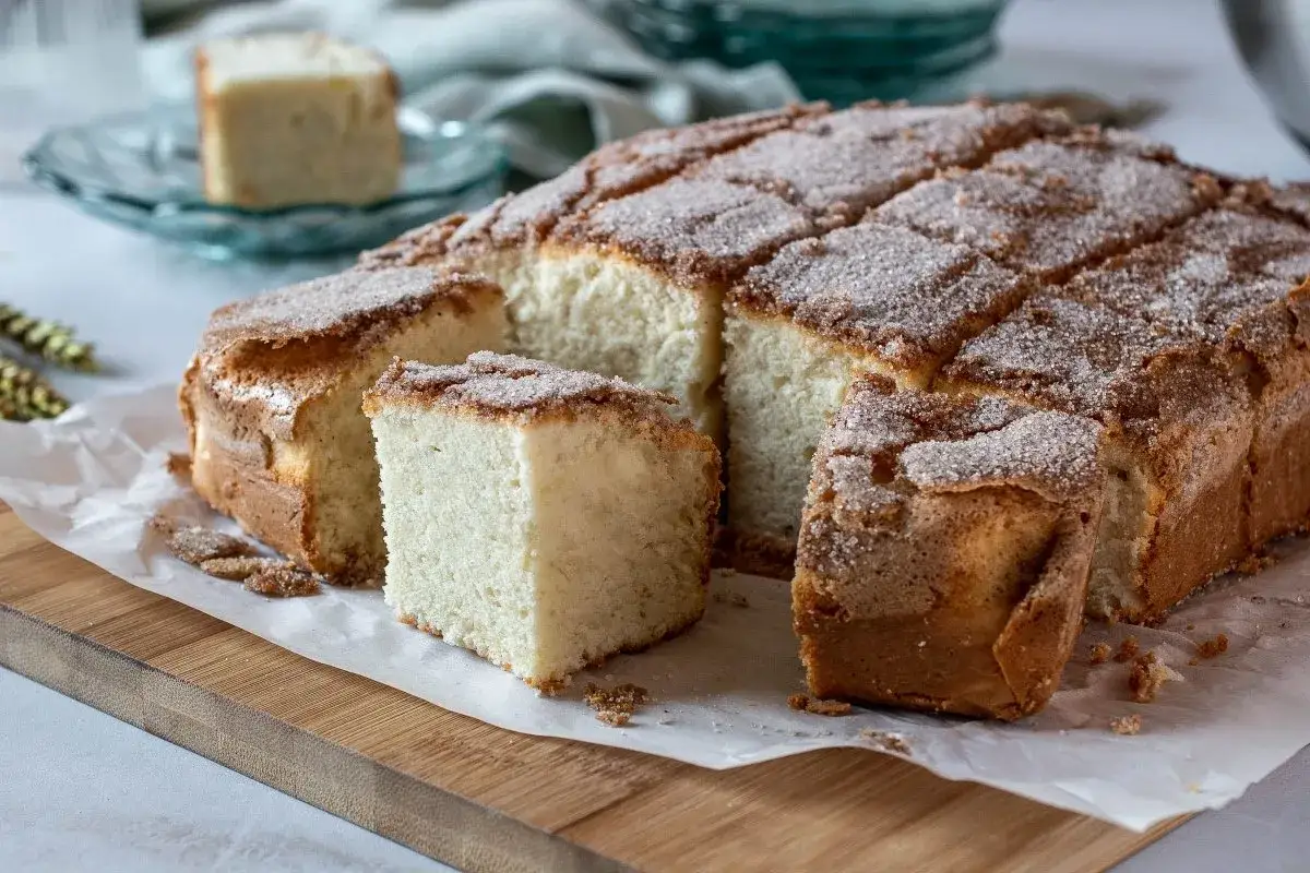 Una bica blanca de Laza, esponjosa y cubierta de az&uacute;car y canela, cortada en porciones sobre papel de horno.