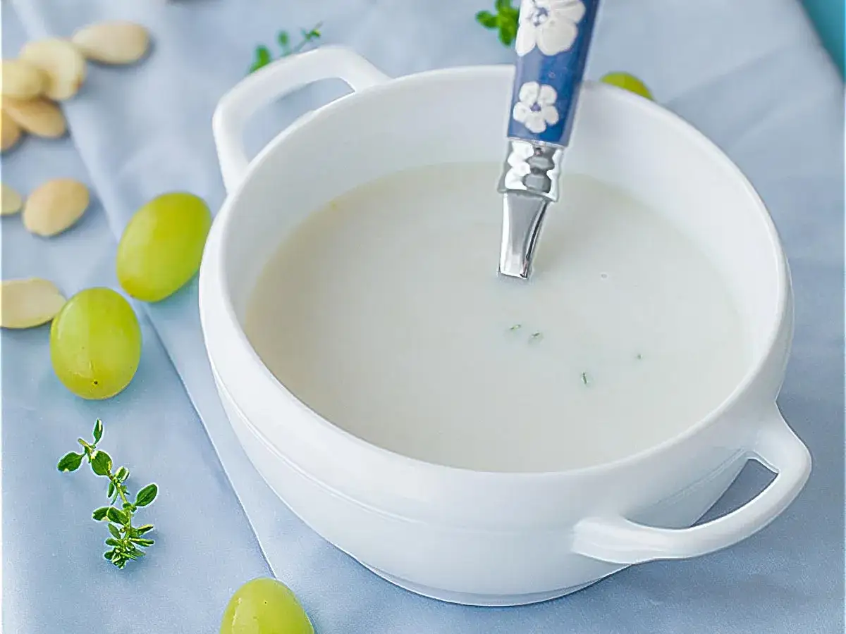 Un cuenco blanco con ajo blanco, uvas verdes y almendras.