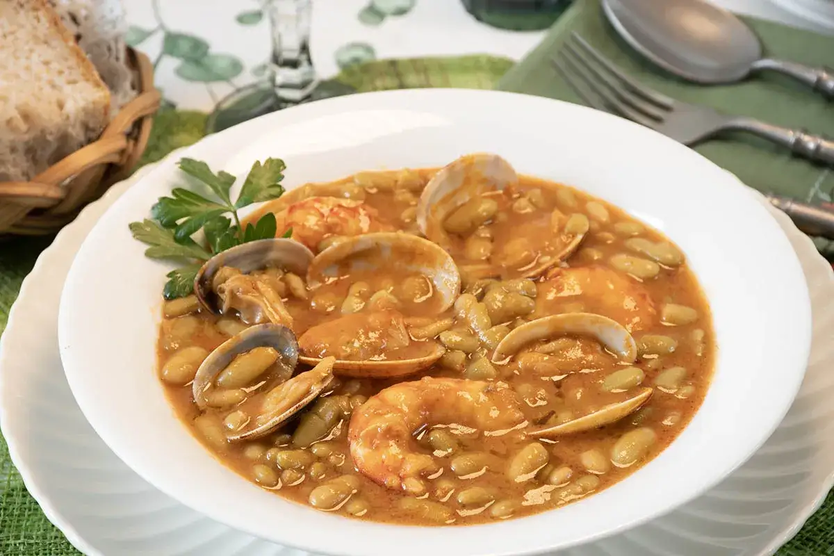 Plato de verdinas asturianas con almejas y gambas, servido en un cuenco blanco. Un ejemplo delicioso de recetas de verdinas asturianas.