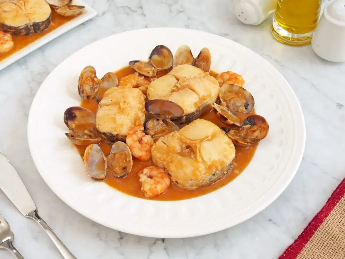 Merluza a la marinera con almejas y gambas, un plato delicioso y lleno de sabor marino.