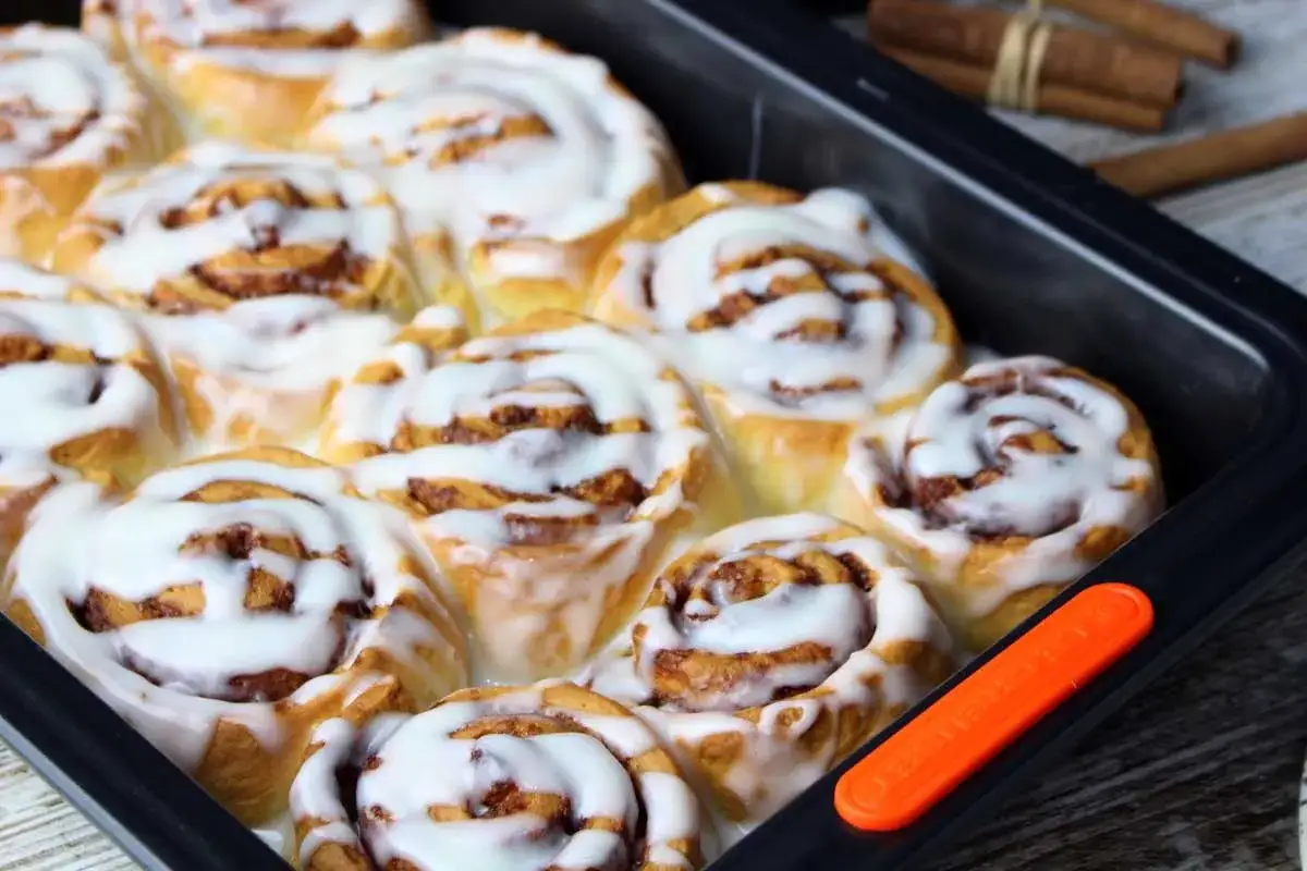 Deliciosos rollitos de canela reci&eacute;n horneados, cubiertos con un glaseado blanco cremoso, listos para ser disfrutados.