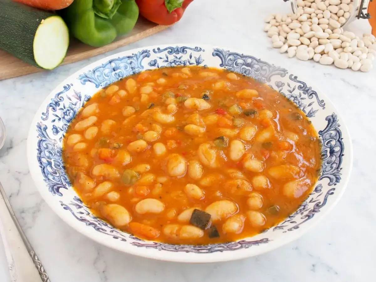Plato de alubias blancas con verduras, un guiso casero y reconfortante.