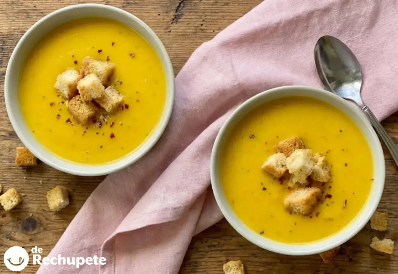 Dos cuencos de cremosa crema de verduras, adornados con picatostes crujientes y un toque de pimentón.