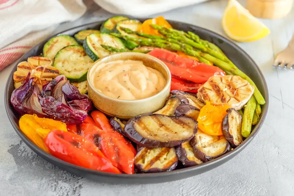 Plato de verduras a la brasa: berenjenas, pimientos, calabac&iacute;n, cebolla morada, esp&aacute;rragos y ajo asado, con una salsa cremosa.
