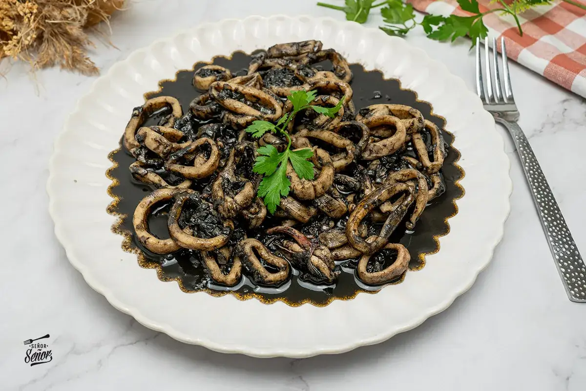Calamares en su tinta, una receta tradicional que deleita el paladar. Anillas de calamar cocinadas en su propia tinta, con un toque de perejil fresco.