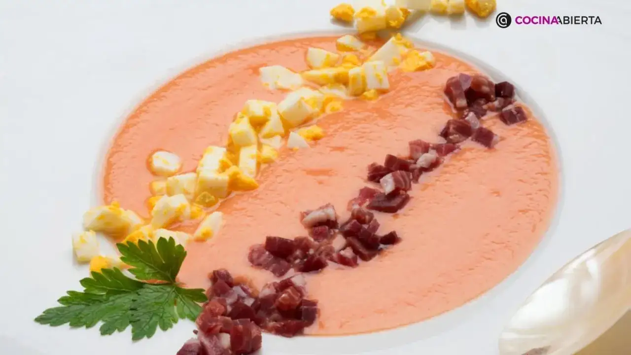Salmorejo cremoso decorado con huevo duro picado y taquitos de jamón serrano. Una deliciosa receta para refrescar tus comidas.